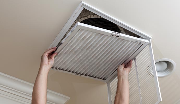 A person is replacing a dirty air filter in an HVAC unit