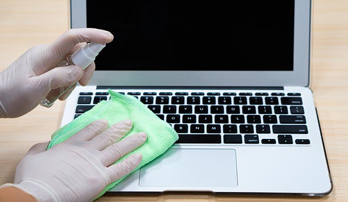 A person is disinfecting a laptop A person is disinfecting a laptop