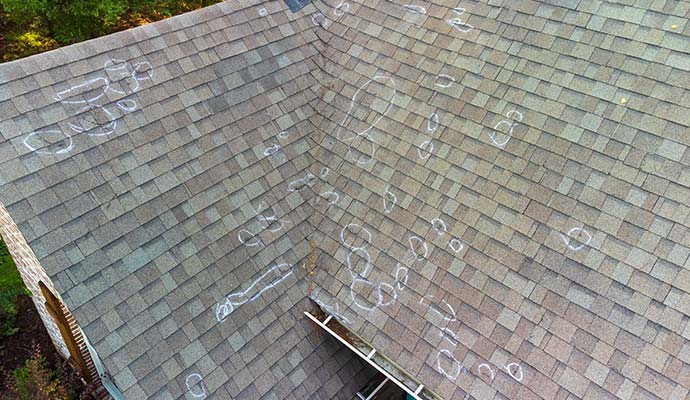 An aerial view of asphalt shingle roof damage, with hail strike marks