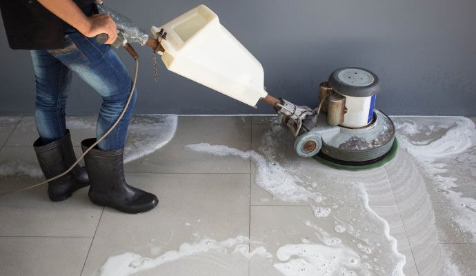 An expert is cleaning a tile floor with a rotary machine An expert is cleaning a tile floor with a rotary machine