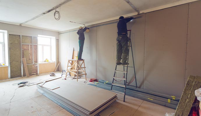 Workers rebuilding a room with new drywall Workers rebuilding a room with new drywall