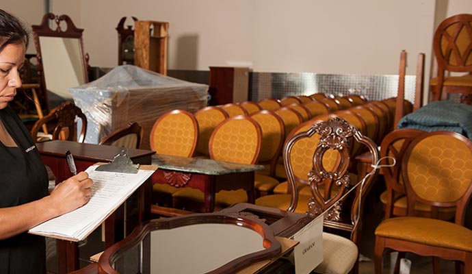 Technician inventorying salvaged furniture for restoration.