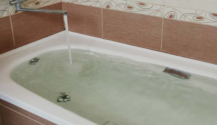 Bathtub filled with water running from a faucet