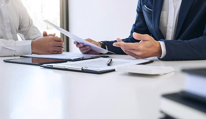 An insurance assistant explaining policy details to a client at a desk A client receiving guidance from an assistant while reviewing an insurance document