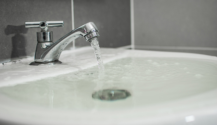 Water running from a faucet into an overflowing bathroom sink