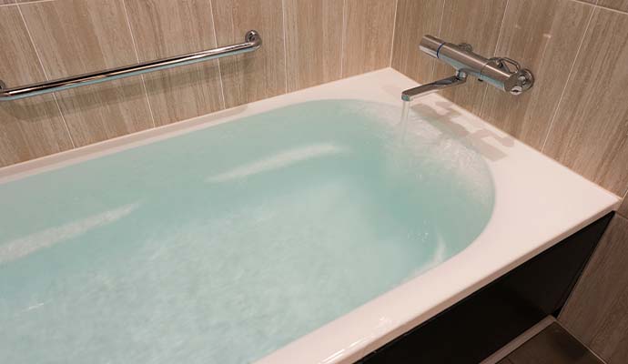 Running faucet filling a bathtub with water