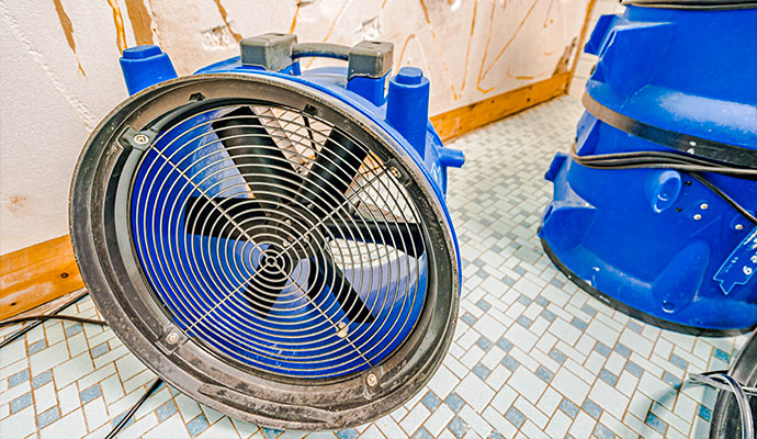 Industrial blue air mover fan placed on tile floor for water drying