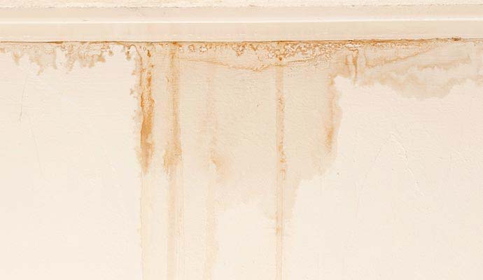 Water stains and drip streaks running down interior wall from attic leak